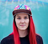 Portrait de Julie, une jeune femme aux cheveux rouges et casquette colorée, décrite comme fêtarde.